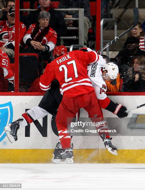 Justin Faulk of the Carolina Hurricanes finishes a check on Colin Greening of the Ottawa Senators during their NHL game at PNC Arena on November 24,...