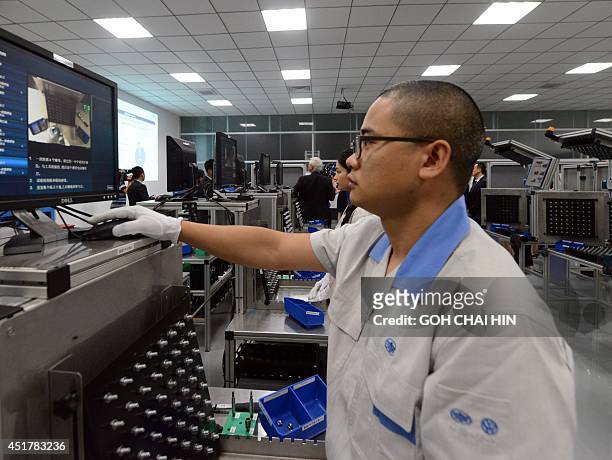 This picture taken on July 6, 2014 shows a Chinese auto worker testing equipments at the R&D department of the FAW-Volkswagen plant in Chengdu,...