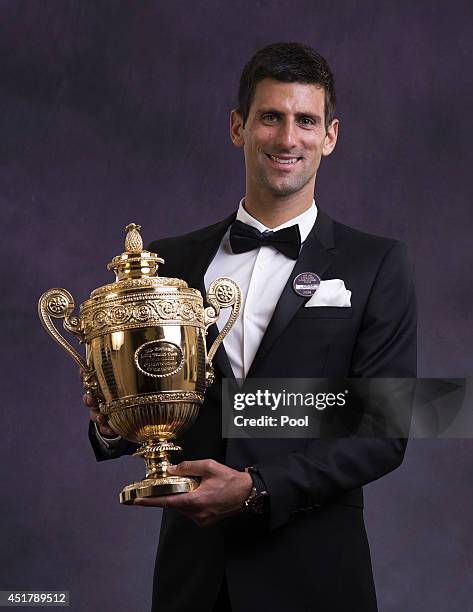 Novak Djokovic of Serbia poses with the Gentlemen's Singles Trophy at the Wimbledon Championships 2014 Winners Ball at The Royal Opera House on July...