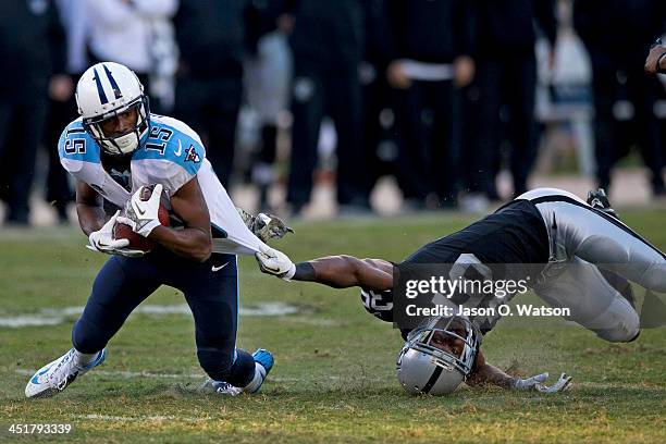Justin Hunter of the Tennessee Titans is tackled by Chimdi Chekwa of the Oakland Raiders during the fourth quarter at O.co Coliseum on November 24,...