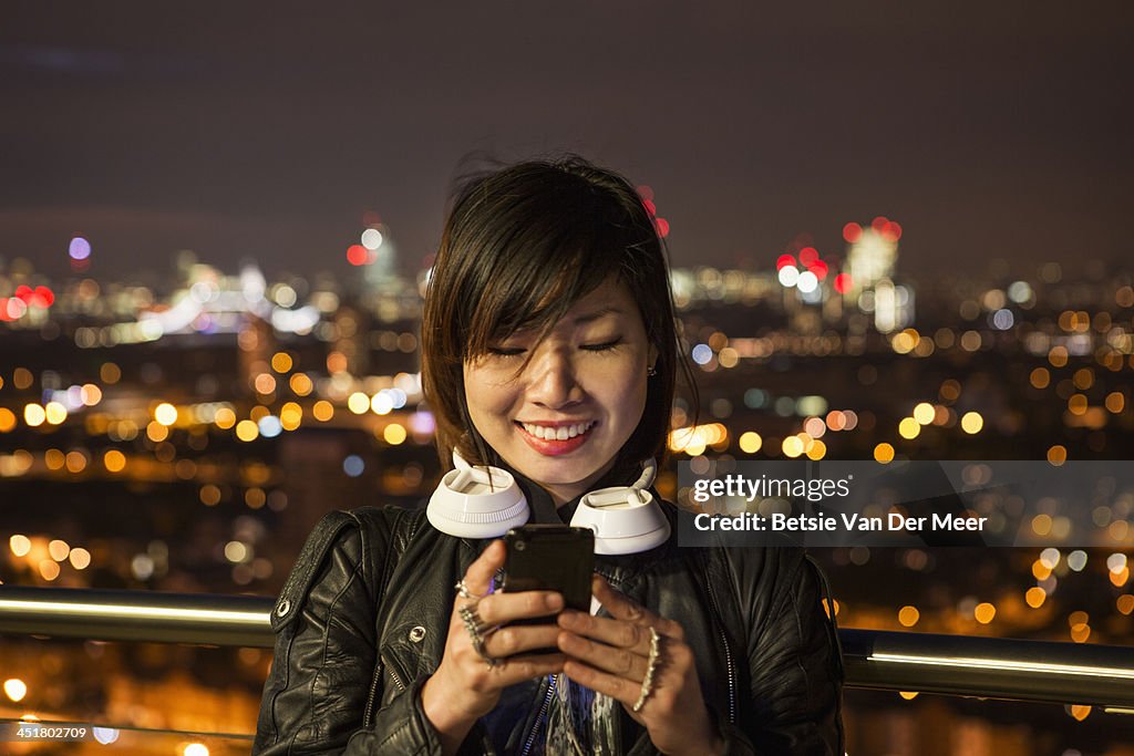 Woman checks mobile phone at night time.