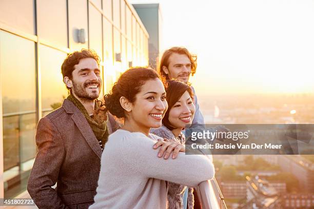 group of friends overlooking city at sunset. - four people stock pictures, royalty-free photos & images