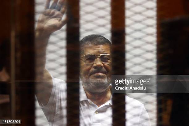 Mohamed Morsi waves as he stands inside a glass defendant's cage during his trial in Cairo, Egypt, on July 07, 2014. An Egyptian court on Monday...
