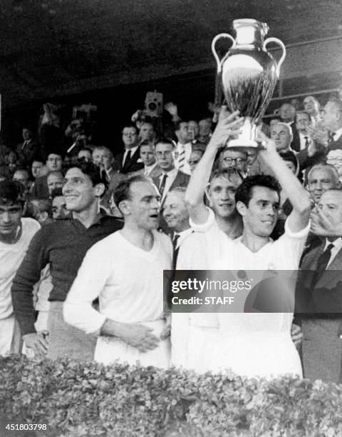 Real Madrid's captain Jose Santamaria, with teammates Rogelio Dominguez and Alfredo Di Stefano standing next to him, holds aloft the European...