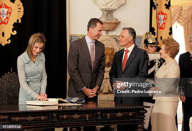 Queen Letizia of Spain signs a guest book as King Felipe VI of Spain speaks with First Lady of Portugal, Maria Cavaco and President Anibal Cavaco...