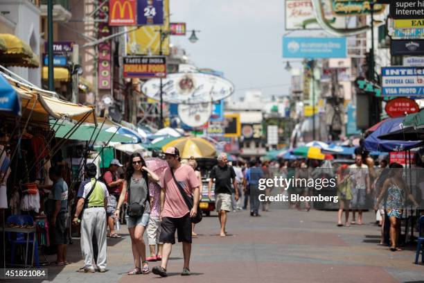 Tourists walk past stalls along Khao San Road in Bangkok, Thailand, on Saturday, June 28, 2014. Through a dozen coups, a tsunami, financial upheaval,...