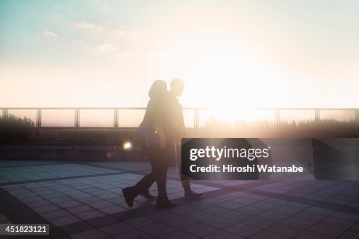 Couple walking on the pavement at sunset Couple walking on the pavement at sunset