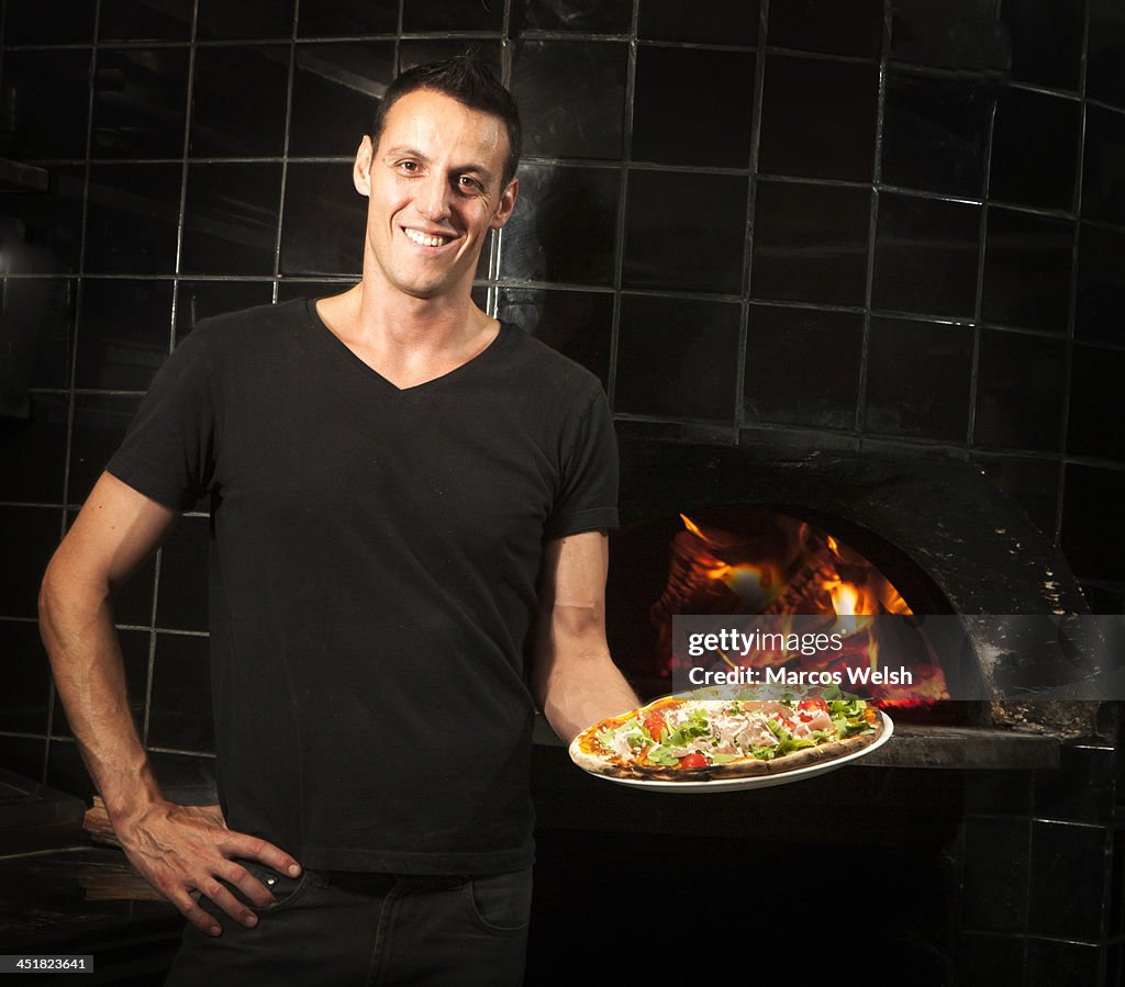 Pizza Chef holding wood fired cooked pizza