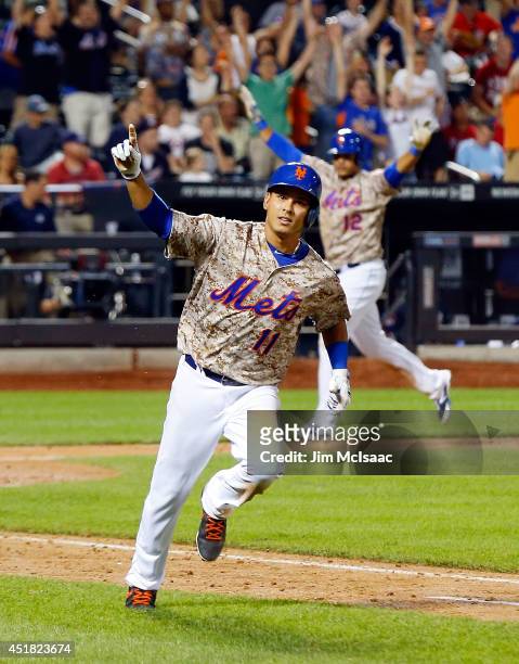Ruben Tejada of the New York Mets celebrates his 11th inning game-winning base hit against the Atlanta Braves while running to first base as teammate...