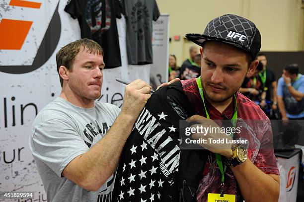 Matt Hughes signs an autograph for fans during the UFC Fan Expo 2014 during UFC International Fight Week at the Mandalay Bay Convention Center on...