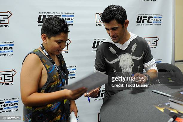Mixed martial artist Dominick Cruz signs autographs for fans during the UFC Fan Expo 2014 during UFC International Fight Week at the Mandalay Bay...