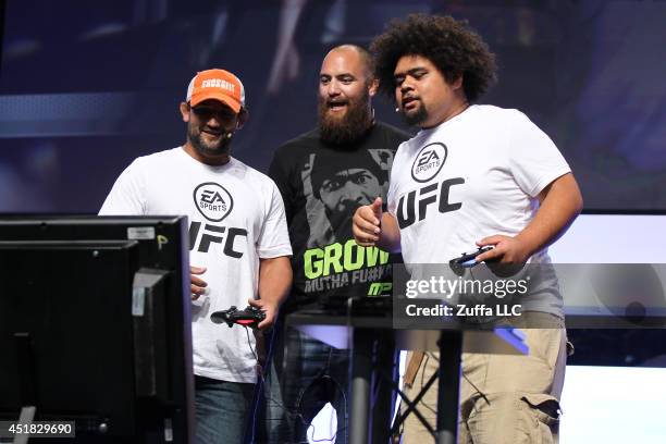 Welterweight champion Johny Hendricks interacts with Travis Browne and a fan while playing the new EA Sports UFC game on the main stage during the...