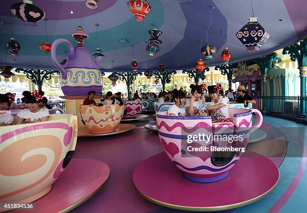 Visitors take a photograph using a smartphone as they ride on the Alice's Tea Party at Tokyo Disneyland, operated by Oriental Land Co., in Urayasu,...