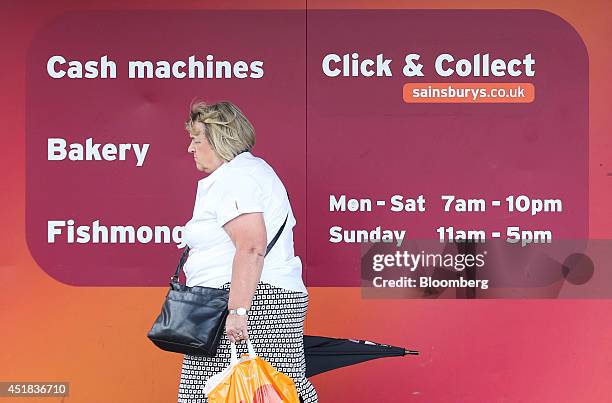 Customer passes a sign advertising Sainsbury's services, including banking and 'Click and Collect,' outside one of the company's supermarket stores,...