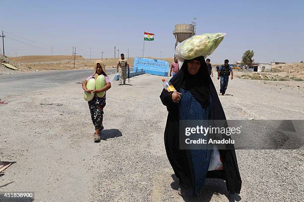 An Iraqi woman and a child fleeing from the ongoing clashes between ISIL-led militants and peshmergas in Jalula towm of Iraq's Diyala carry their...