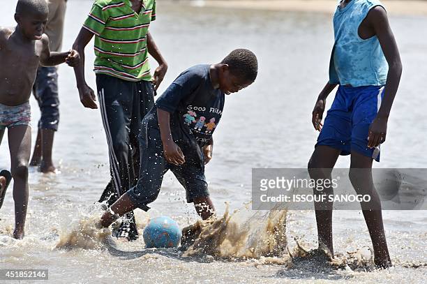 Young boys play football in a flooded street in the Adjoufou district of Abidjan on July 8 following a month of heavy rainfalls over the country's...