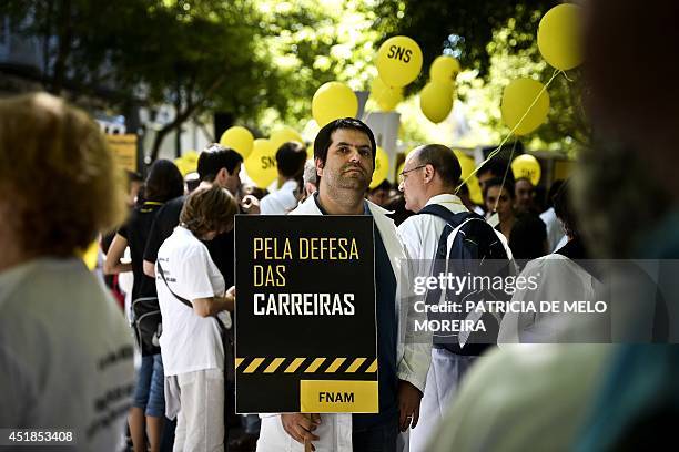 Demonstrator holds a placard reading "In defense of our careers" in Lisbon on July 8 as hundreds of doctors in white smocks protest in front of the...