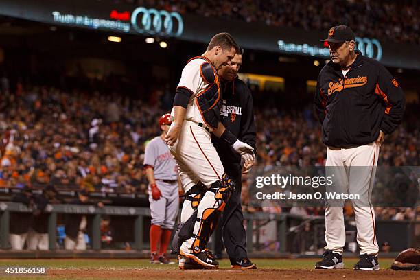 Buster Posey of the San Francisco Giants is examined by head athletic trainer Dave Groeschner and manager Bruce Bochy after getting hit with a foul...
