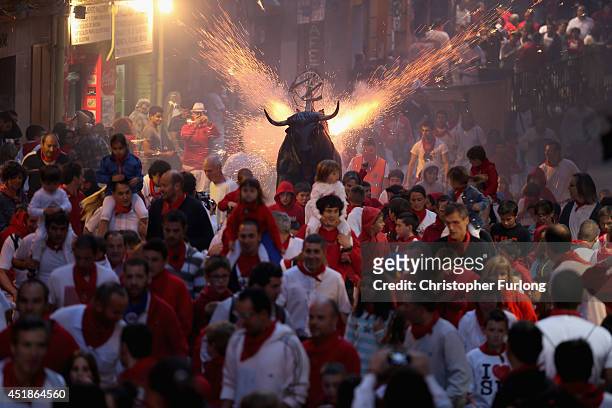People and children are chased by a Toro del Fuego as it is runs through the streets of Pamplona on the third day of the San Fermin Running Of The...