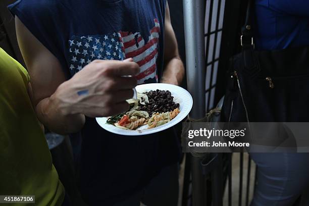 Soccer fan eats from a plate of traditional Brazilian feijoada during the semifinal World Cup game against Germany on July 8, 2014 in Port Chester,...