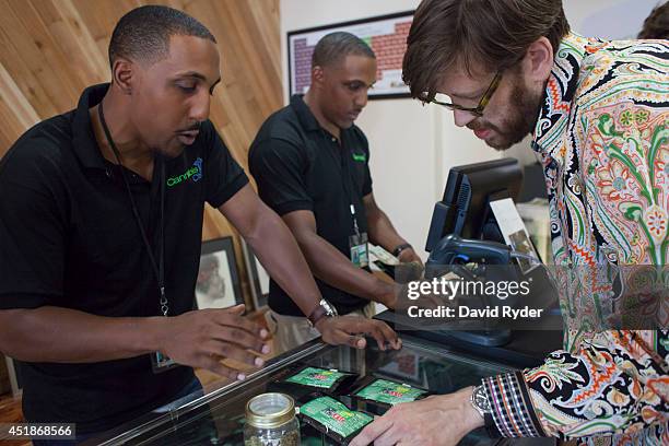 Identical twins Adam Powers and Andrew Powers serve customer Michael Merithew at the Cannabis City retail marijuana store on July 8, 2014 in Seattle,...