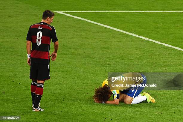 David Luiz of Brazil reacts after being defeated 7-1 by Germany as Mesut Oezil of Germany looks on during the 2014 FIFA World Cup Brazil Semi Final...