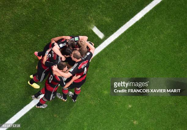 Germany's forward Thomas Mueller celebrates with teammates after scoring during the semi-final football match between Brazil and Germany at The...