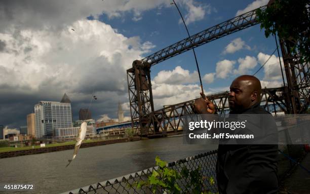 Tommy Greer fishes in the Cuyahoga River with a background of downtown Cleveland, which has been chosen for the 2016 Republican National Convention,...