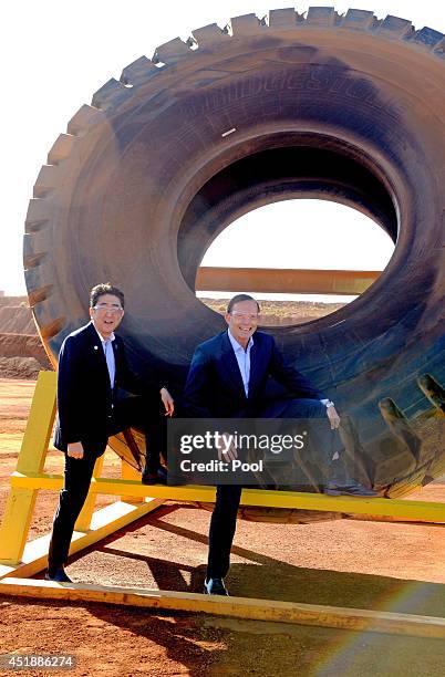 Prime Minister Tony Abbott and Japanese Prime Minister Shinzo Abe pose for a photograph next to a haulage truck tyre during a tour of the Rio Tinto...