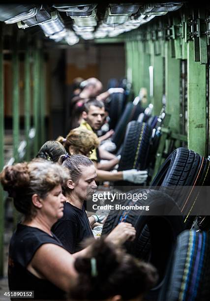 Workers inspect the quality of newly formed automobile tires during production at the Continental AG plant in Timisoara, Romania, on Wednesday, June...