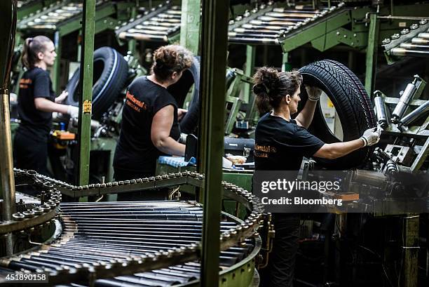 Workers inspect the quality of newly formed automobile tires during production at the Continental AG plant in Timisoara, Romania, on Wednesday, June...