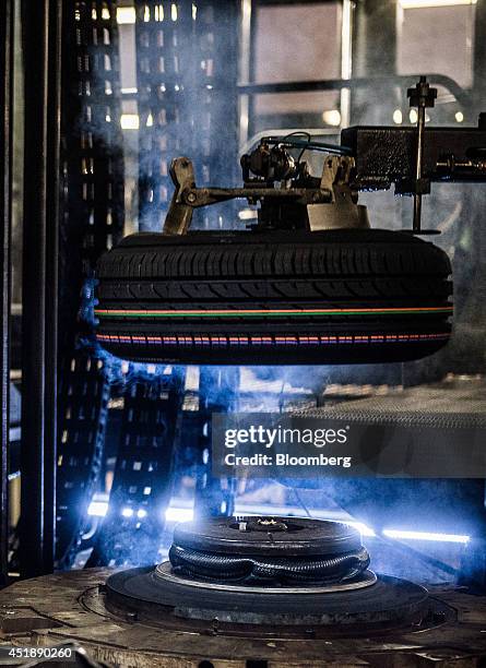 An automobile tire is moved onto a moulding machine during production at the Continental AG plant in Timisoara, Romania, on Wednesday, June 25, 2014....