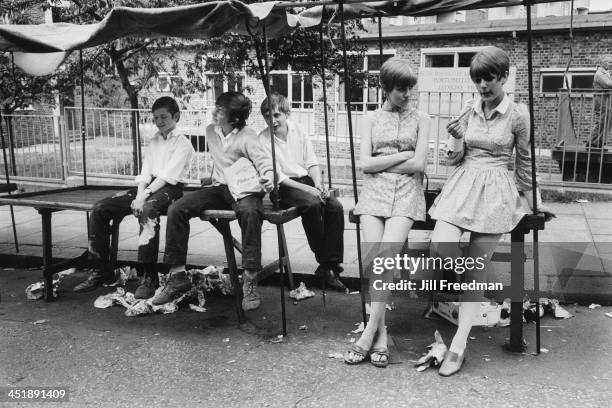 Group of young people sit on the empty market stalls in Portobello Road, London, circa 1969.