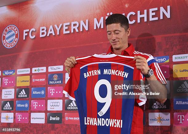 New FC Bayern Muenchen player Robert Lewandowski looks at his new jersey during his presentation at the Bayern Muenchen training ground on July 9,...