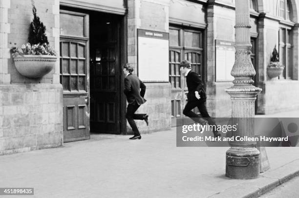 Ringo Starr and John Lennon from The Beatles run through the entrance of Marylebone Station in London during the filming of 'A Hard Day's Night' on...