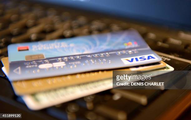 Credit cards are pictured on a laptop keyboard on July 8, 2014 in Lille. AFP PHOTO / DENIS CHARLET