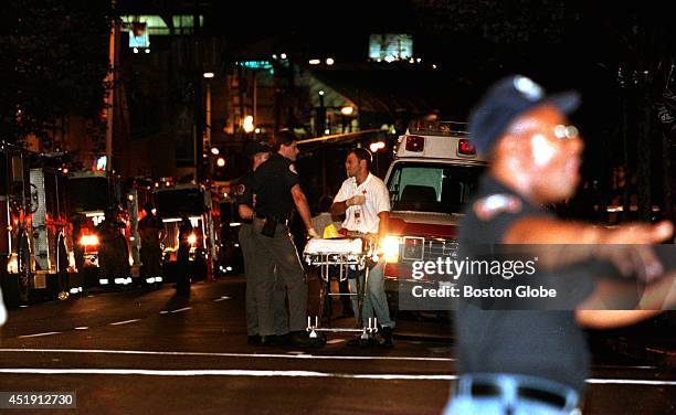 Police officer directs people away from the street that leads to Centennial Olympic Park. In the background, an ambulance crew waits to see if they...