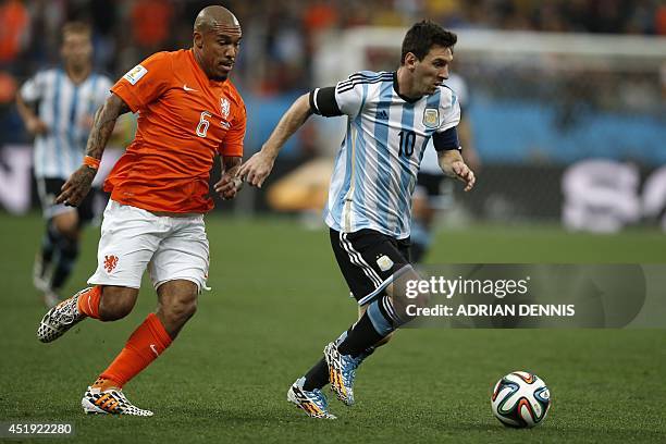 Netherlands' midfielder Nigel de Jong and Argentina's forward and captain Lionel Messi vie for the ball during the semi-final football match between...
