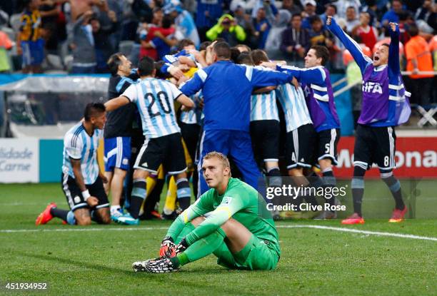 Jasper Cillessen of the Netherlands sits on the pitch after failing to save the penalty kick of Maxi Rodriguez of Argentina as Argentina celebrate...