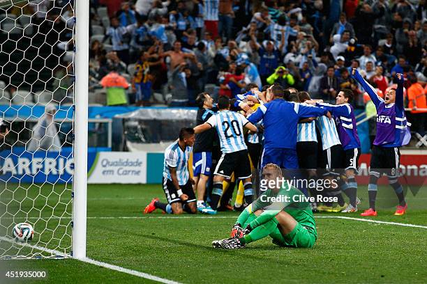 Jasper Cillessen of the Netherlands sits on the pitch after failing to save the penalty kick of Maxi Rodriguez of Argentina as Argentina celebrate...