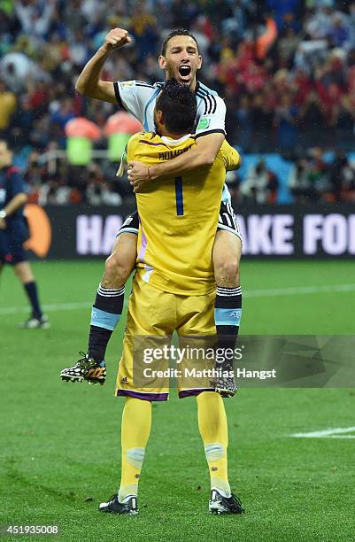 Maxi Rodriguez of Argentina celebrates with goalkeeper Sergio Romero after making his penalty kick to defeat the Netherlands in a shootout during the...
