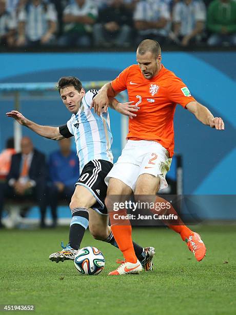 Lionel Messi of Argentina and Ron Vlaar of the Netherlands challenge for the ball during the 2014 FIFA World Cup Brazil Semi Final match between...