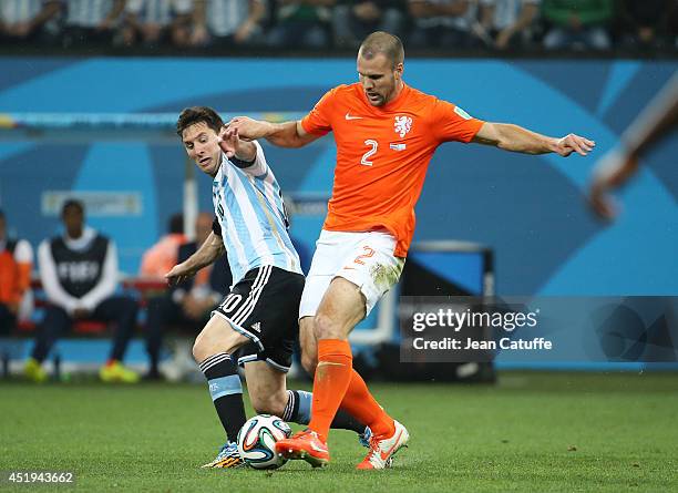 Lionel Messi of Argentina and Ron Vlaar of the Netherlands challenge for the ball during the 2014 FIFA World Cup Brazil Semi Final match between...