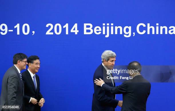 China's Vice Premier Wang Yang and U.S. Secretary of the Treasury Jack Lew look at U.S. Secretary of State John Kerry shaking hands with China's...