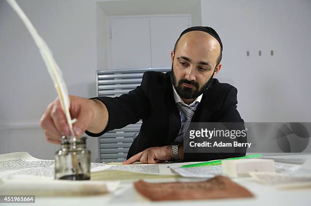 Rabbi and Torah Scribe Reuven Yaacobov refills his quill pen as he copies by hand a section of the Torah on July 10, 2014 in the Jewish Museum in...