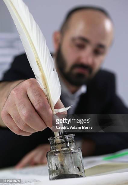 Rabbi and Torah Scribe Reuven Yaacobov refills his quill pen as he copies by hand a section of the Torah on July 10, 2014 in the Jewish Museum in...