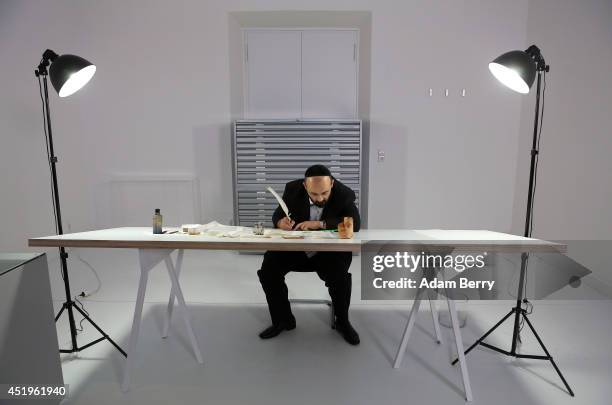 Rabbi and Torah Scribe Reuven Yaacobov copies by hand a section of the Torah with a quill pen on July 10, 2014 in the Jewish Museum in Berlin,...