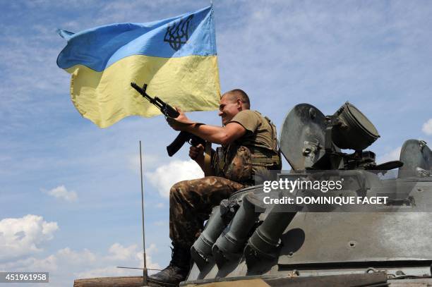 Ukrainian government soldier sits atop an armoured vehicle around 20 Km south of Donetsk on July 10, 2014. Ukrainian forces have massed tanks and...