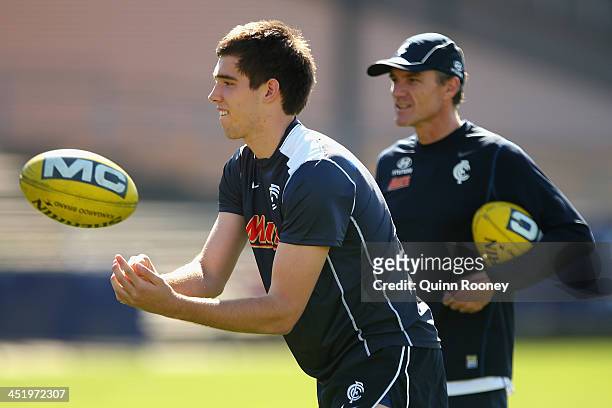 Cameron Giles of the Blues handballs whilst Dean Laidley the assistant coach looks on during a Carlton Blues AFL training session at Visy Park on...