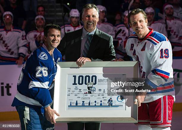 Martin St. Louis of the Tampa Bay Lightning is presented with a commemorative plaque celebrating his 1,000th NHL game from former teammates Dave...